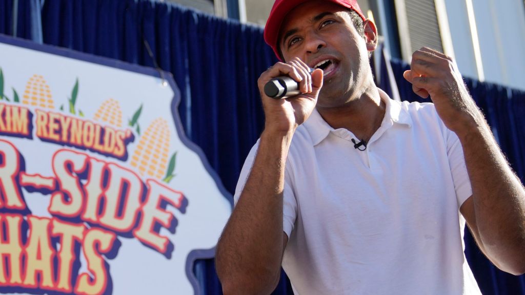 Vivek Ramaswamy sings into a microphone in front of a sign for the Kim Reynolds' fair-side chats event.