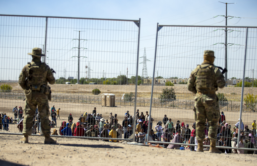 Migrants wait in line adjacent to the border fence under the watch of the Texas National Guard to enter into El Paso, Texas, May 10, 2023. Border Patrol does not have protocols for assessing medical needs of children with preexisting conditions, according to an independent report made public Tuesday, July 18, on the death of an 8-year-old girl from Panama who was in federal custody. (AP Photo/Andres Leighton, File)