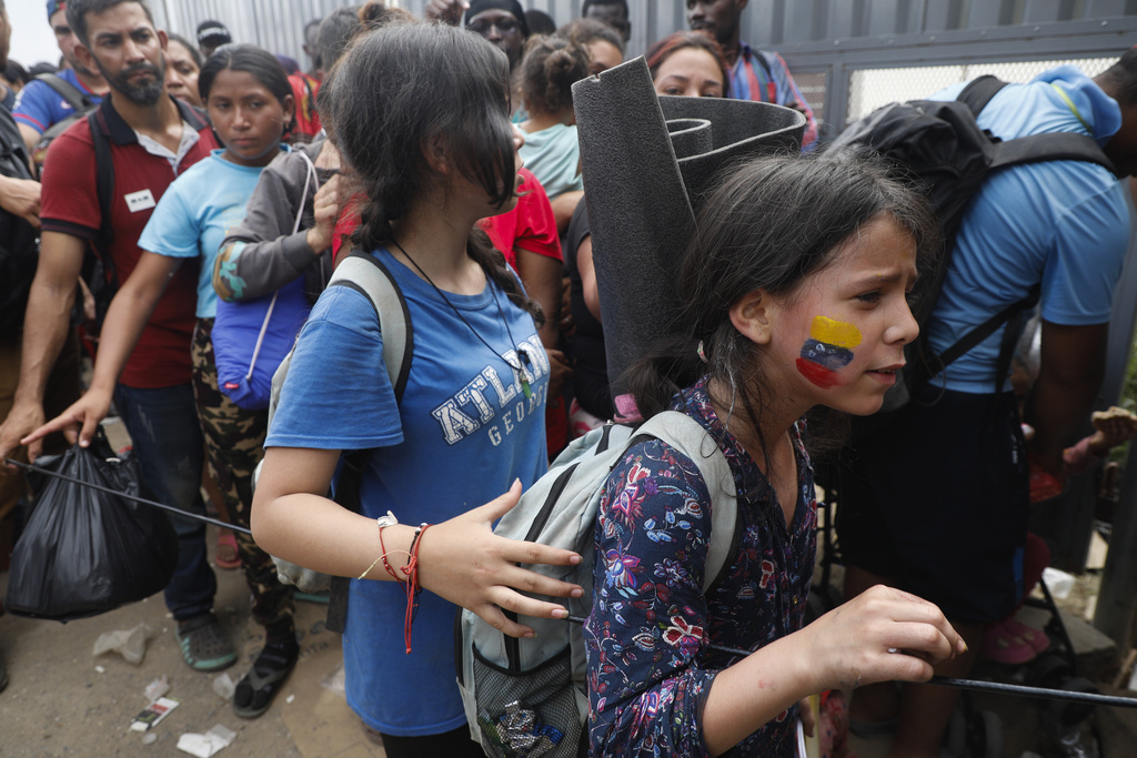 A migrant girl with the colors of the Venezuelan flag painted on her cheek lines up to acquire a Honduras Migration transit permit to continue on her way north to Guatemala and hopefully to the Mexico-United States border, in Danlí, Honduras, Wednesday, Oct. 11, 2023. (AP Photo/Elmer Martinez)