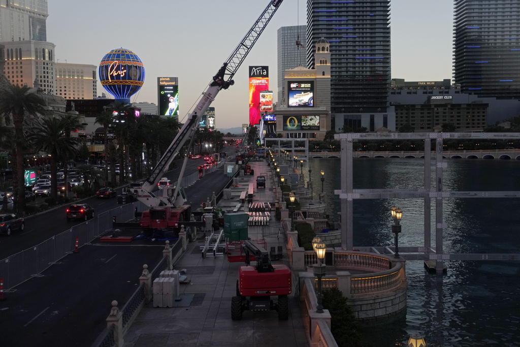 Pedestrians take an escalator along the Las Vegas Strip beside rigging and fencing installed ahead of the Las Vegas Formula One Grand Prix auto race Friday, Nov. 10, 2023, in Las Vegas. (AP Photo/John Locher)