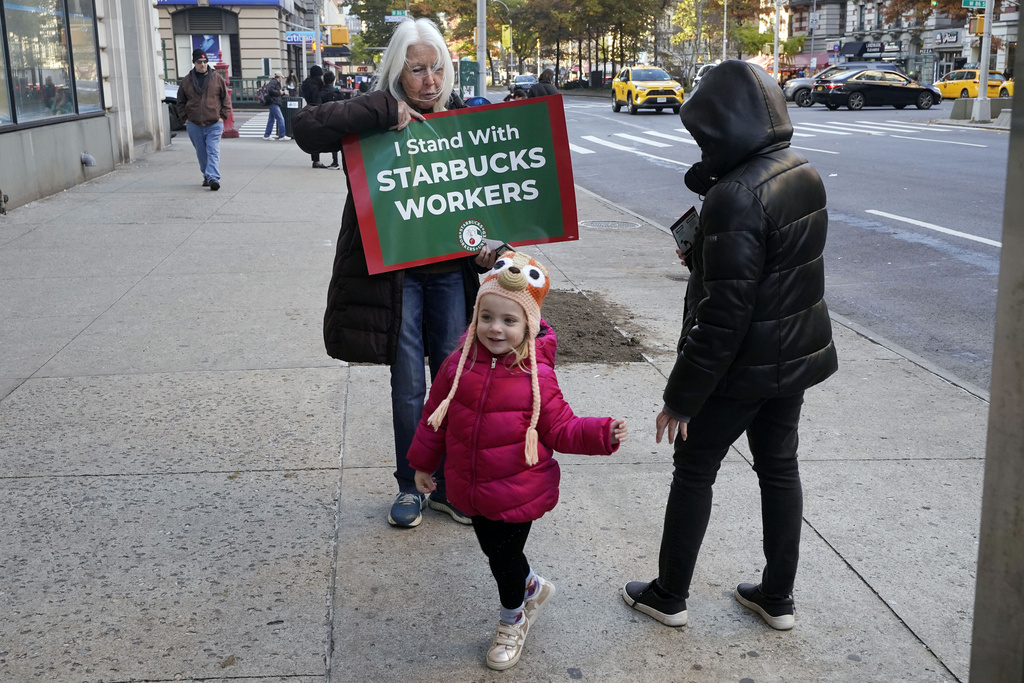 Isabel Johnston holds a sign supporting Starbucks workers outside a Starbucks on New York's Upper West Side, Thursday, Nov. 16, 2023. Thousands of workers at more than 200 U.S. Starbucks stores plan to walk off the job Thursday in what organizers say is the largest strike yet in the two-year-old effort to unionize the company's stores. (AP Photo/Richard Drew)