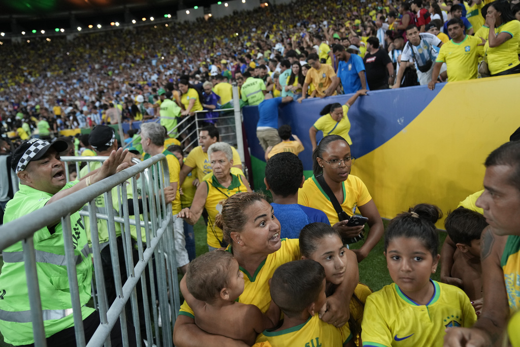A woman tries to protect children after a fight between Brazilian and Argentina fans at the stands prior to a qualifying soccer match for the FIFA World Cup 2026 at Maracana stadium in Rio de Janeiro, Brazil, Tuesday, Nov. 21, 2023. (AP Photo/Silvia Izquierdo)