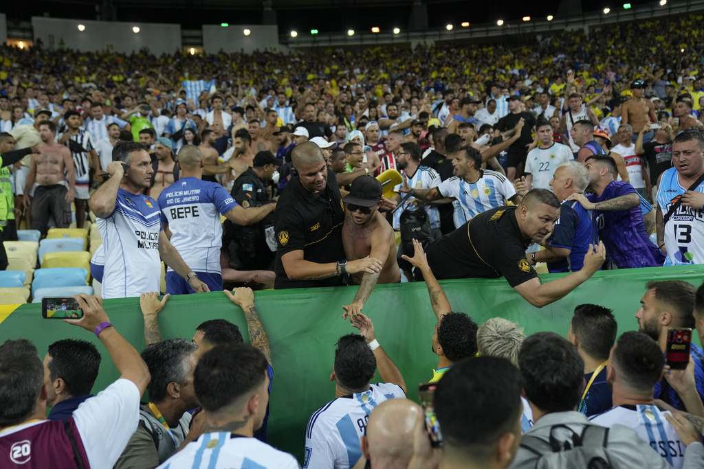 Players of Argentina try to calm the crowd after a fight between Brazilian and Argentinian fans broke out in the stands prior to a qualifying soccer match for the FIFA World Cup 2026 at Maracana stadium in Rio de Janeiro, Brazil, Tuesday, Nov. 21, 2023. (AP Photo/Silvia Izquierdo)