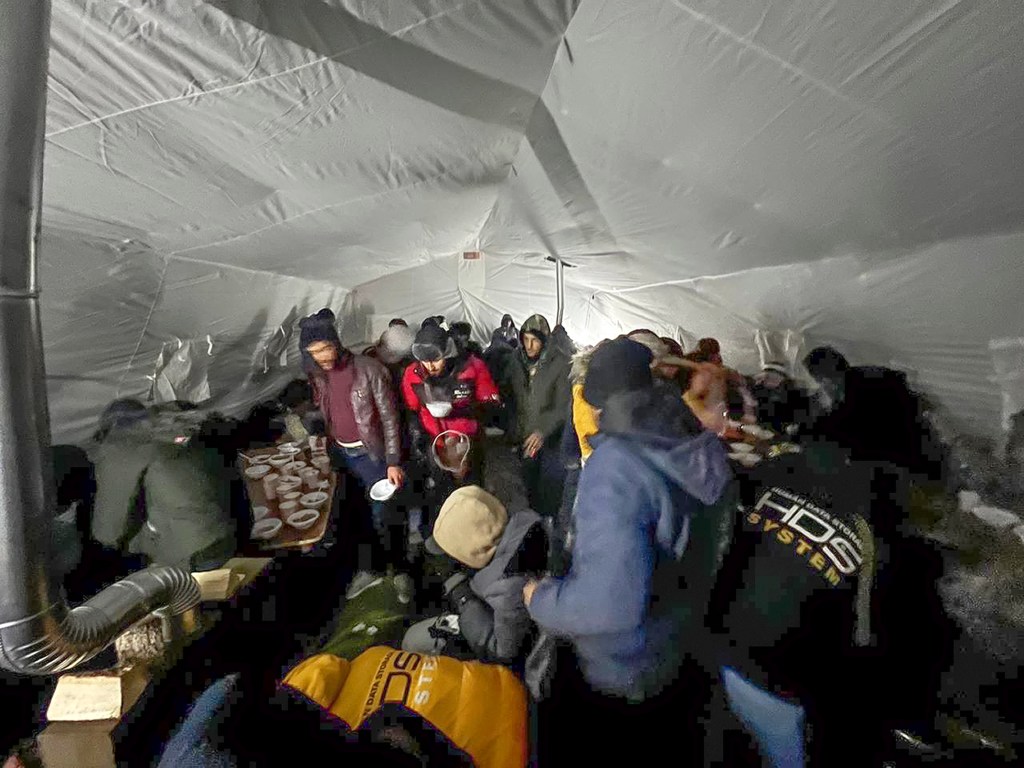 In this handout photo released by Governor of Murmansk region Andrey Chibis' telegram channel on Wednesday, Nov. 22, 2023, migrants gather getting hot drinks inside a tent near the border with Finland at the Salla checkpoint, one of the still open border checkpoints situated in the Kandalaksha district of the Murmansk region, about 1300 km (812 miles) north of Moscow, Russia. (Governor of Murmansk region Andrey Chibis' telegram channel via AP)