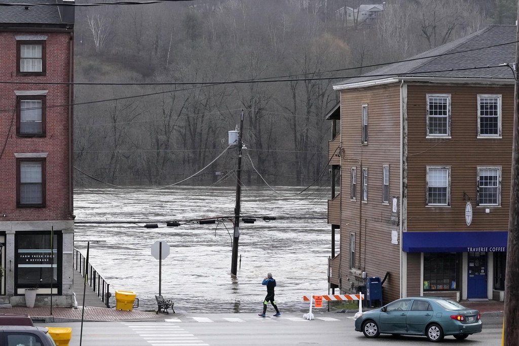 A man photographs the flooded Kennebec River, Tuesday, Dec. 19, 2023, in Hallowell, Maine. Waters continue to rise following Monday's severe storm. (AP Photo/Robert F. Bukaty)