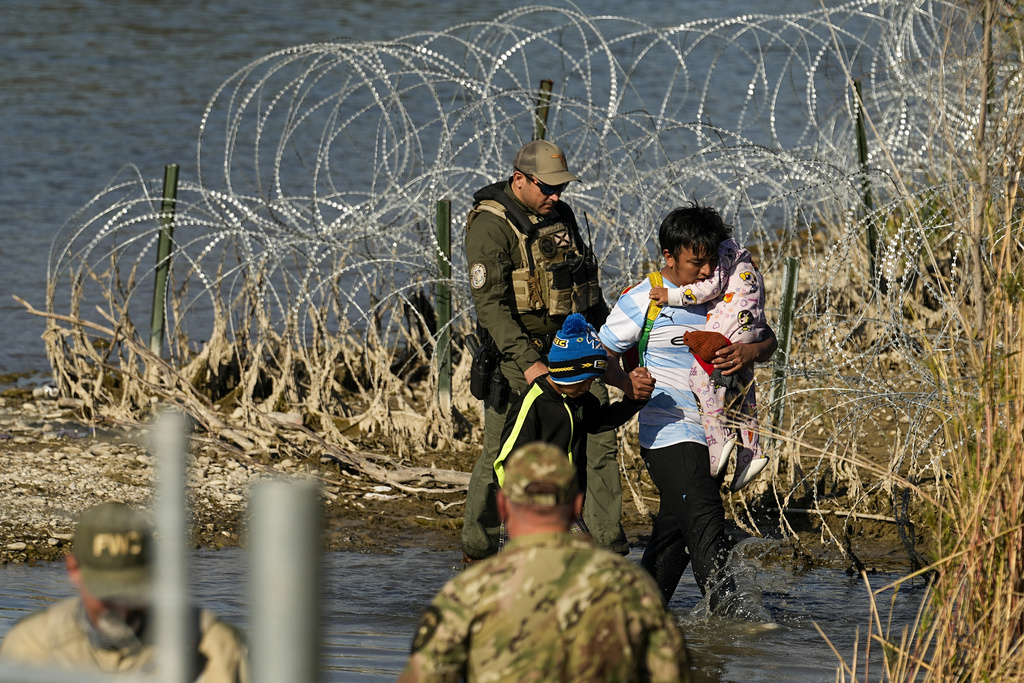 Migrants are taken into custody by officials at the Texas-Mexico border, Wednesday, Jan. 3, 2024, in Eagle Pass, Texas. U.S. House Speaker Mike Johnson is leading about 60 fellow Republicans in Congress on a visit to the Mexican border. Their trip comes as they are demanding hard-line immigration policies in exchange for backing President Joe Biden's emergency wartime funding request for Ukraine. (AP Photo/Eric Gay)