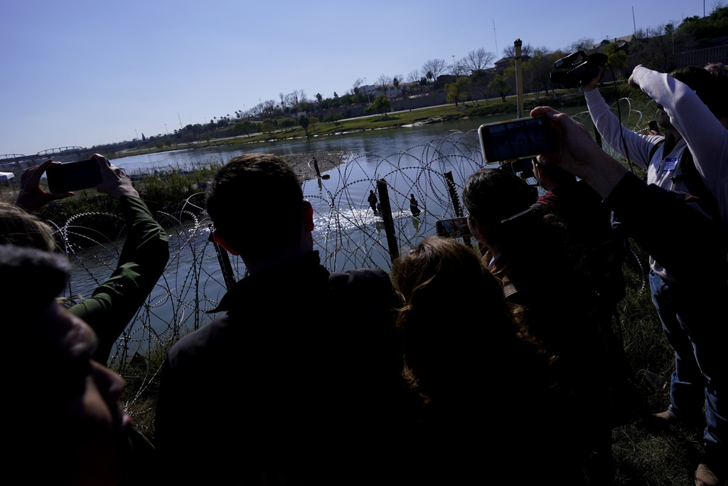 Republican members of Congress look on as migrants cross the Rio Grande at the Texas-Mexico border, Wednesday, Jan. 3, 2024, in Eagle Pass, Texas. (AP Photo/Eric Gay)