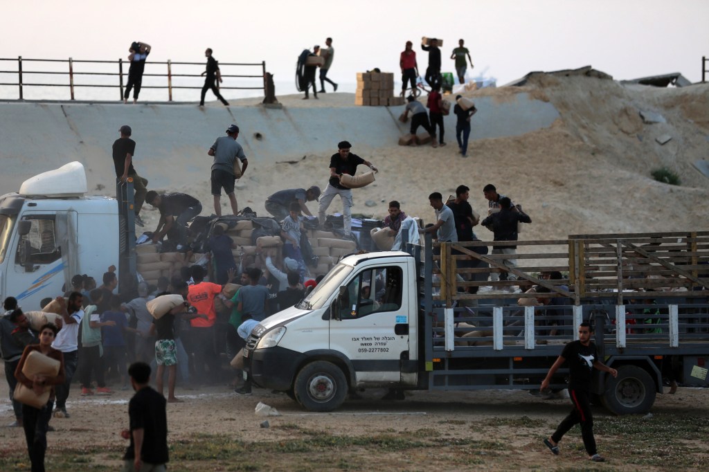 Palestinians are climbing onto trucks to grab aid that is being delivered into Gaza through a U.S.-built pier, amid the ongoing conflict between Israel and the Palestinian Islamist group Hamas, as seen from central Gaza Strip, on May 18, 2024. (Photo by Majdi Fathi/NurPhoto via Getty Images)